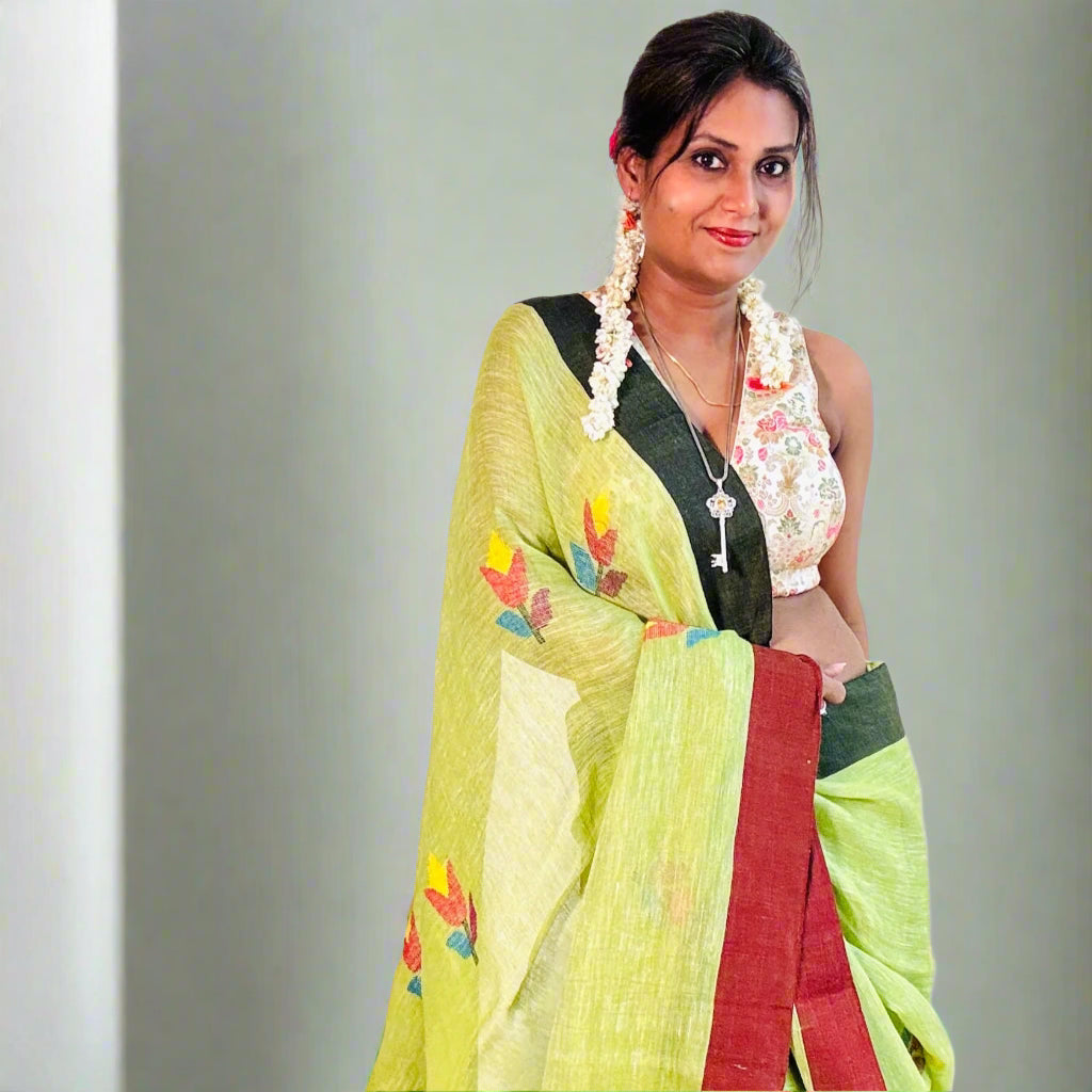Woman wearing a green saree with floral patterns on a plain background