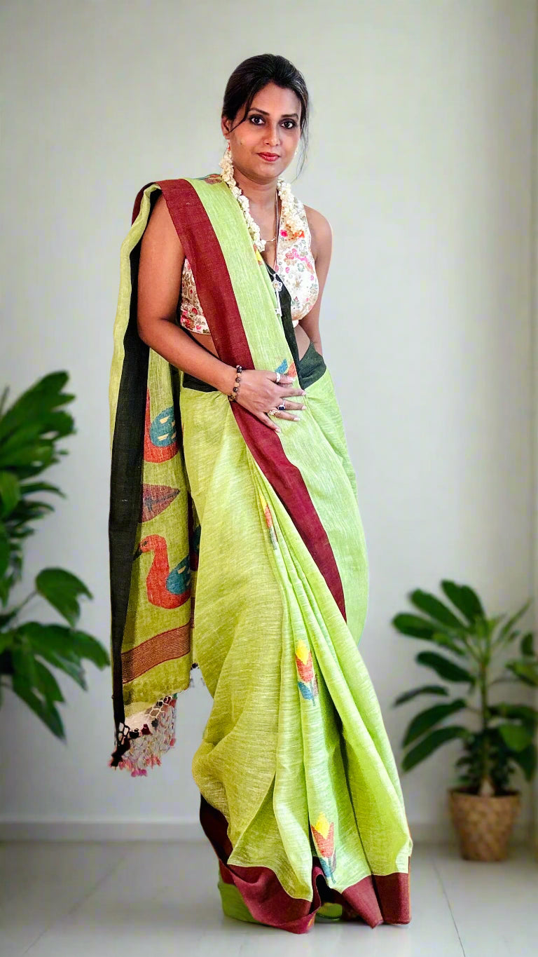 Woman wearing a green saree with a red border indoors.