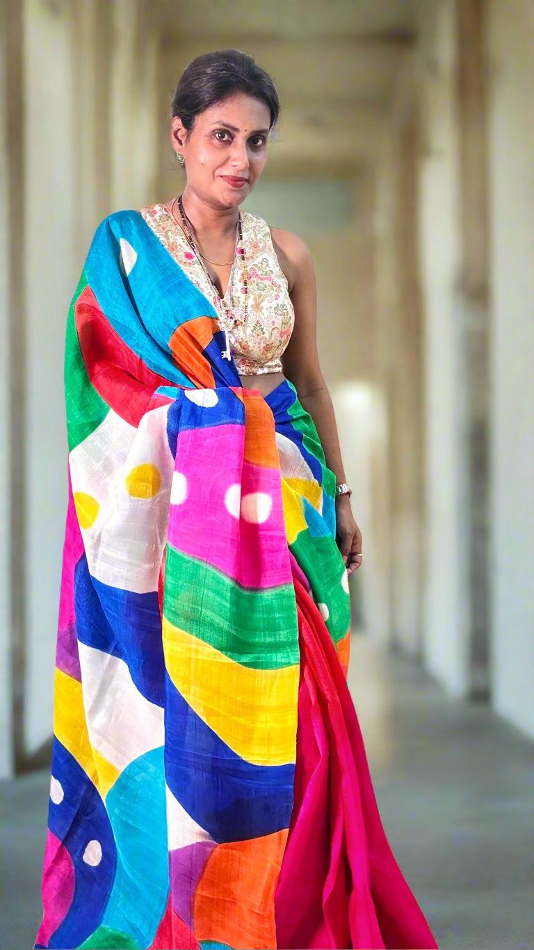 Woman wearing a colorful saree with a white blouse indoors.